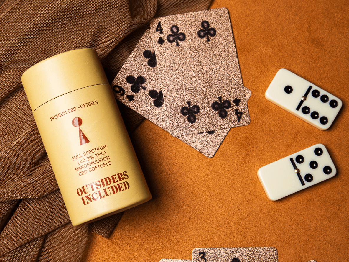 A table with playing cards, dominoes, and a soft-gel container
