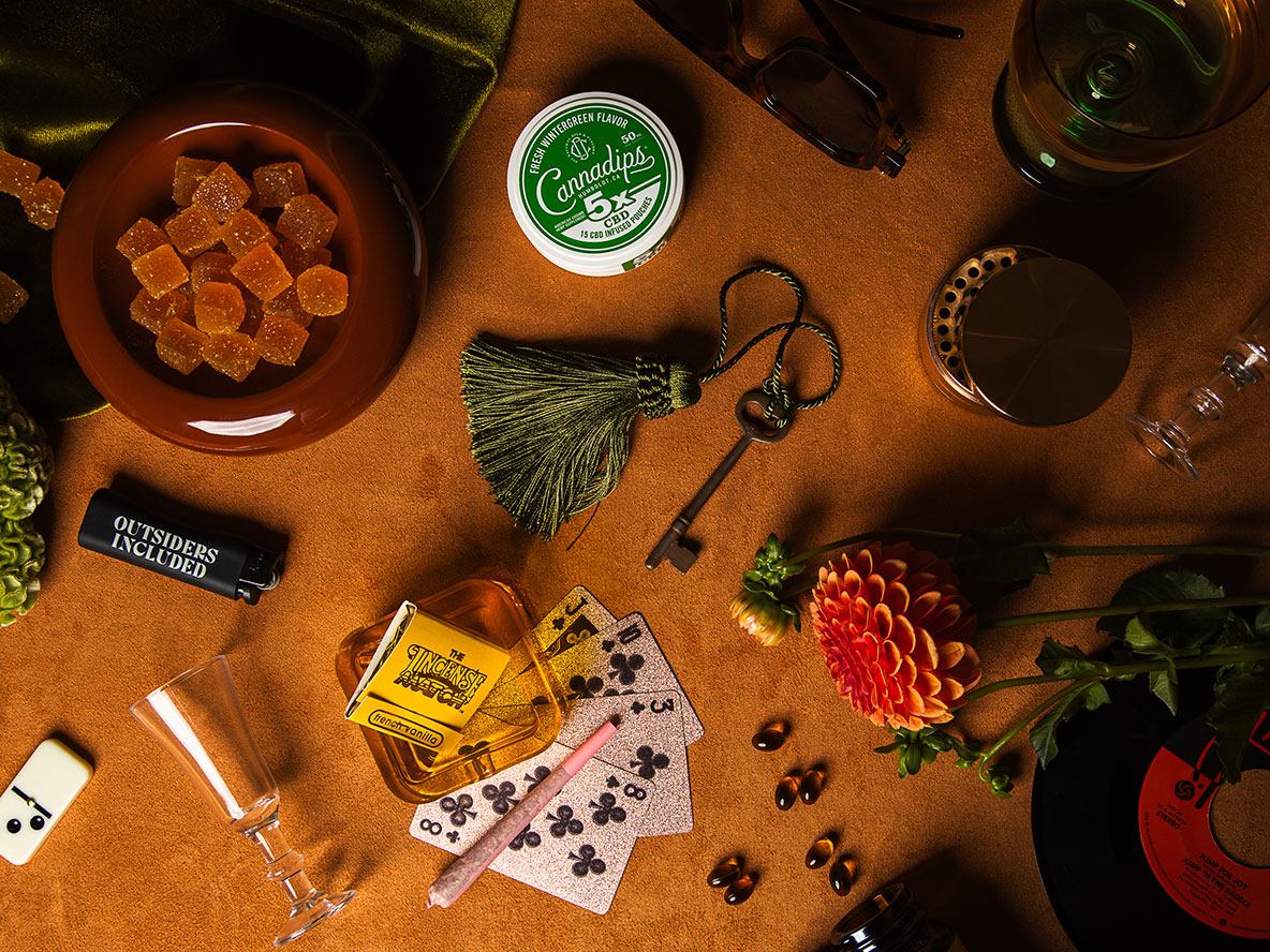 A table with a bowl of gummies, a skeleton key with a tassle, playing cards and various products